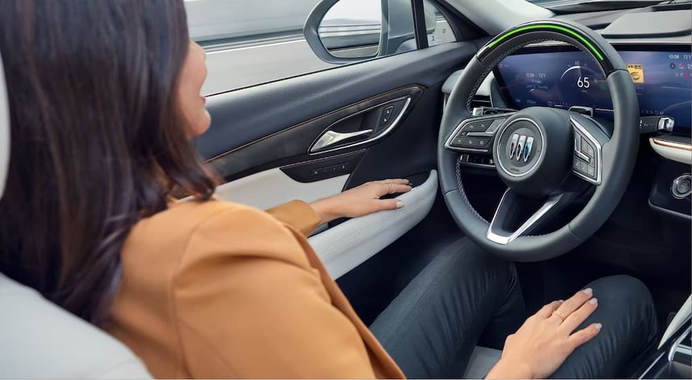 A woman is shown seated in the drivers seat of a 2024 Buick Envision.
