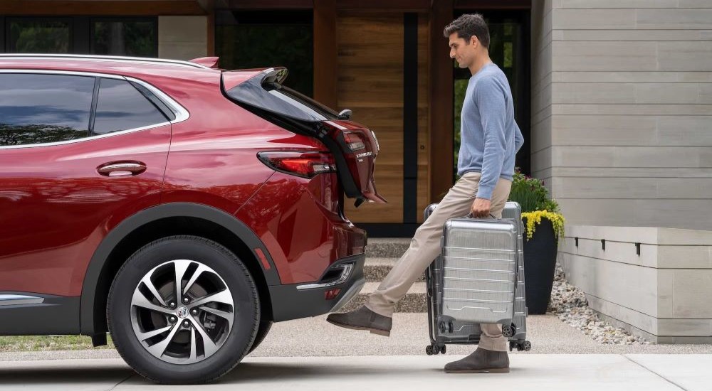 A man loading luggage into a red 2024 Buick Envision.