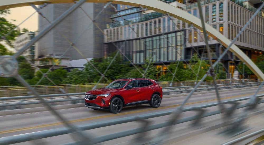 A red 2024 Buick Envision driving through a city.