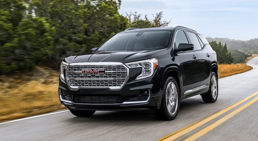 A black 2024 GMC Terrain Denali driving on a highway.