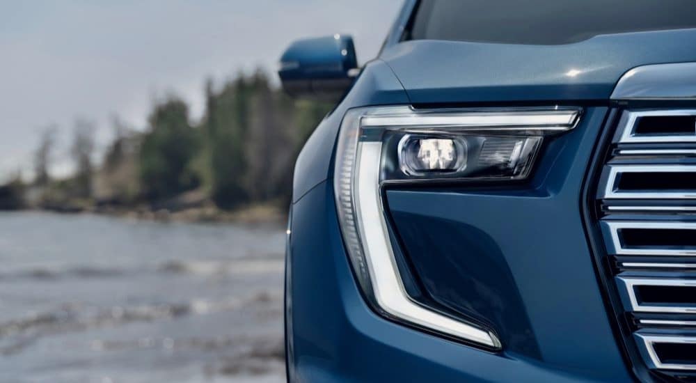 A close-up on the headlights of a blue 2024 GMC Acadia Denali.