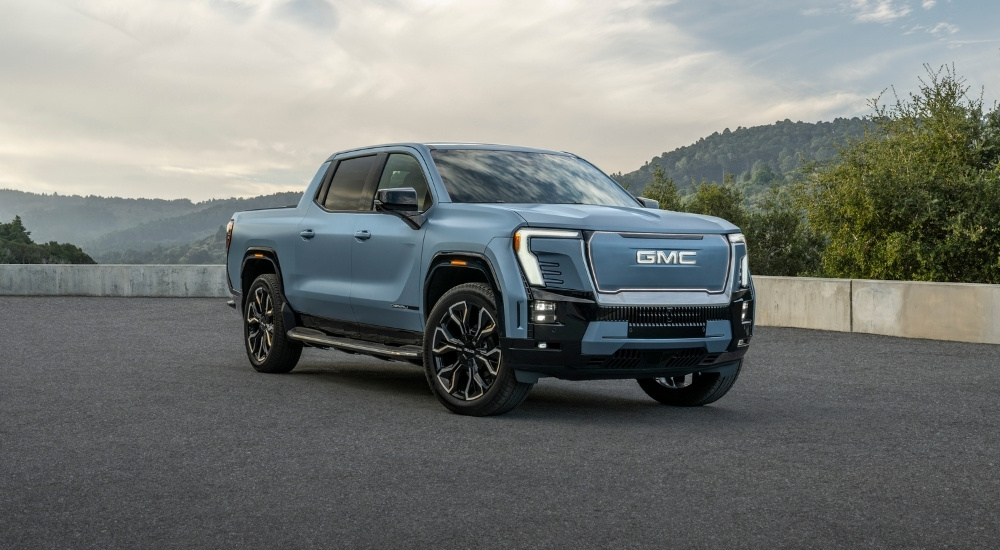 A blue 2025 GMC Sierra EV Denali is shown from the front at an angle.