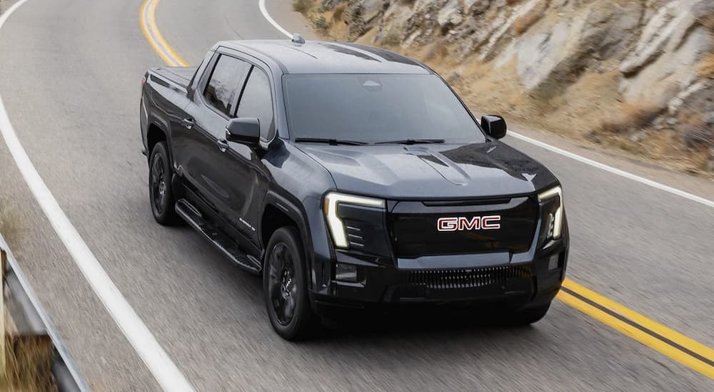 Black 2026 GMC Sierra EV Elevation for sale driving down a winding road.