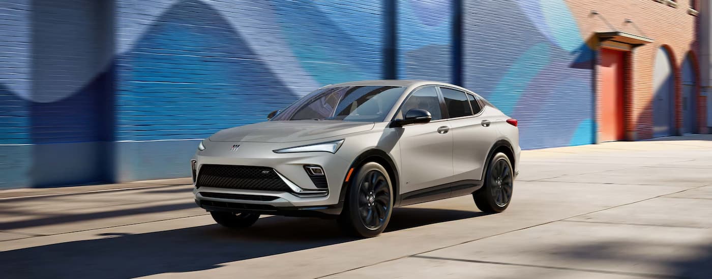 A silver 2026 Buick Envista driving by a painted brick wall.