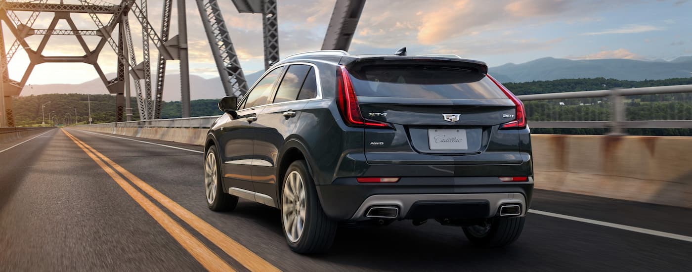 Rear of a blue 2020 Cadillac XT4 driving across a bridge.