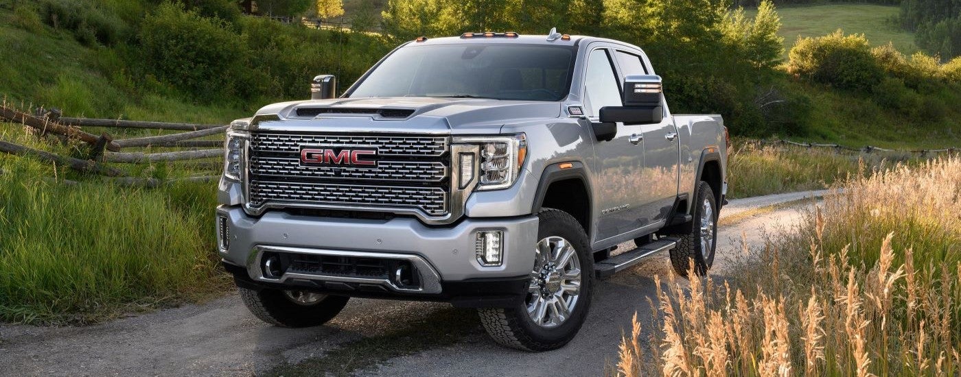 White 2021 GMC Sierra 2500HD Denali driving down a trail.