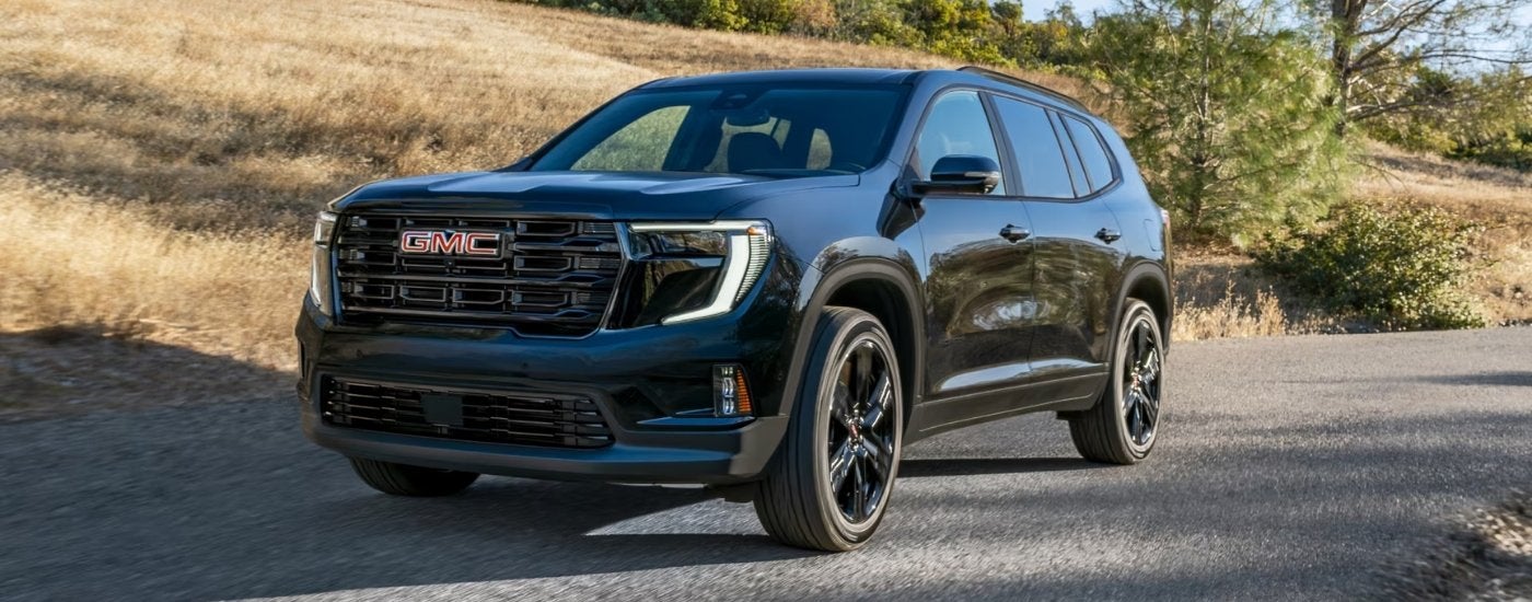 Black 2026 GMC Acadia Elevation driving down an open road