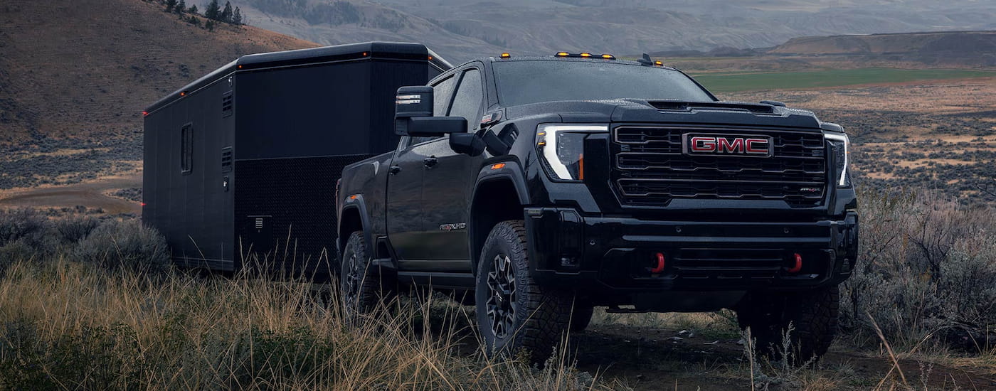 Black 2026 GMC Sierra 2500 HD towing a trailer.