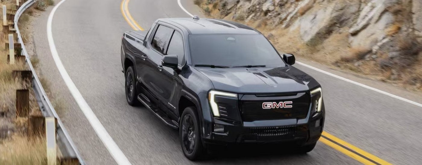 A black 2026 GMC Sierra EV Elevation driving on a highway.