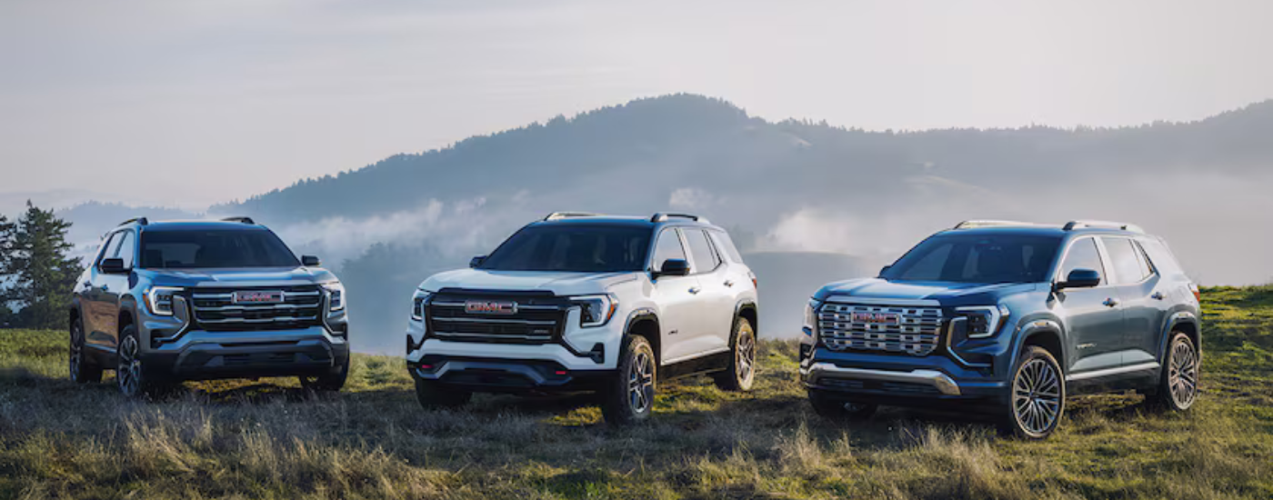 Two blue and a white 2026 GMC Terrains parked off road