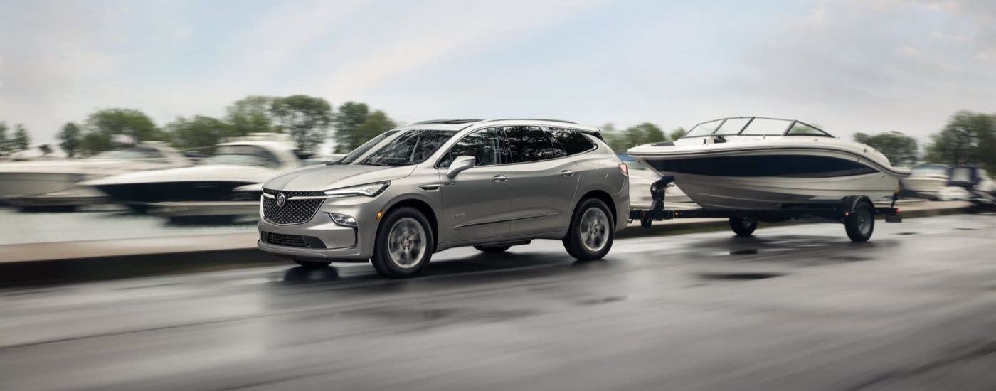 A silver 2022 Buick Enclave Avenir is shown towing a boat after visiting a Buick dealer.