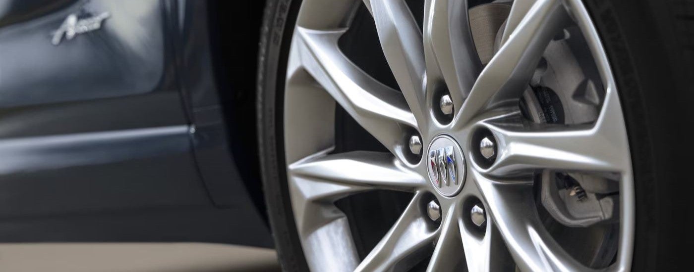 A close up shows a chrome rim on a blue 2024 Buick Encore GX Avenir.