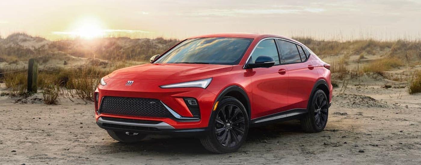 A red 2024 Buick Envista is shown parked on a beach after leaving a Buick dealer near Brighton.