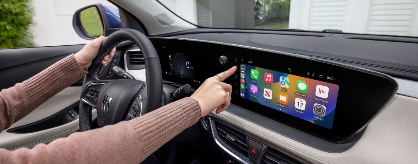 A person is shown using the infotainment screen in a 2024 Buick Encore GX Avenir.