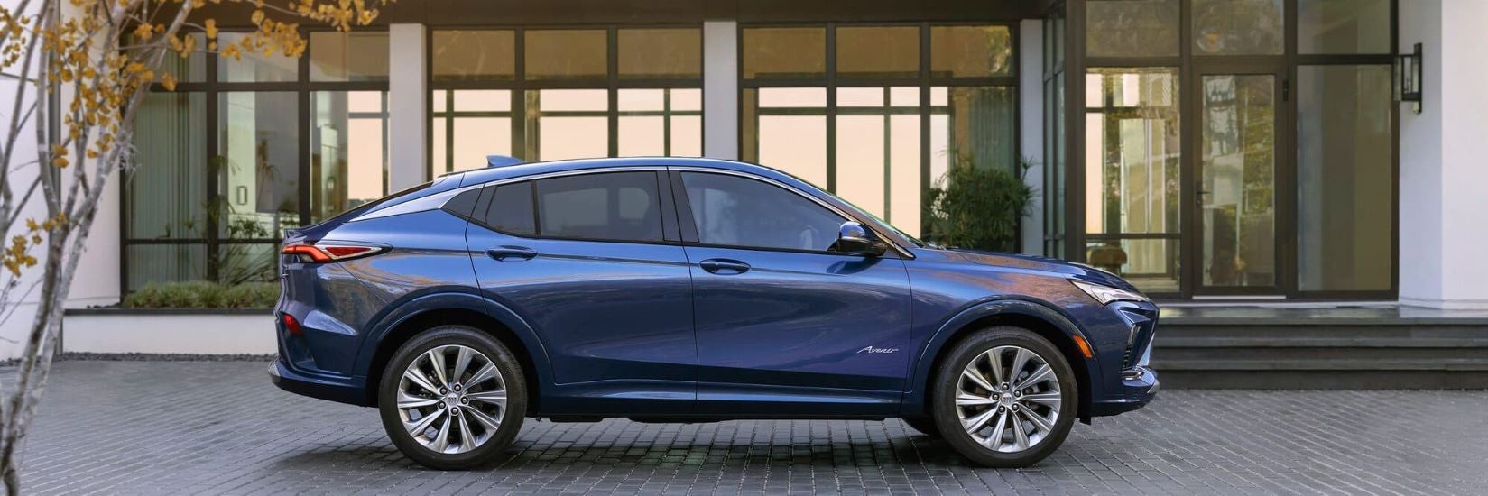 Side of blue 2024 Buick Envista Avenir parked outside a building.