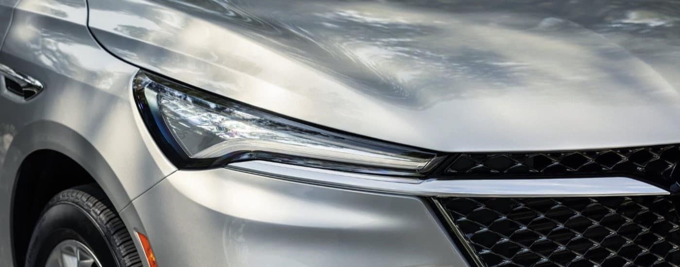 A close-up on the headlights of a silver 2024 Buick Enclave Avenir is shown.