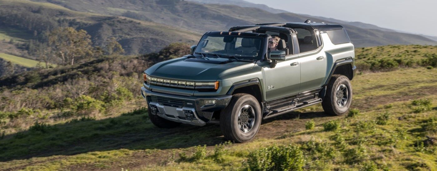 A green 2024 GMC Hummer EV parked off-road on a trailer after visiting a dealer with EVs for sale.