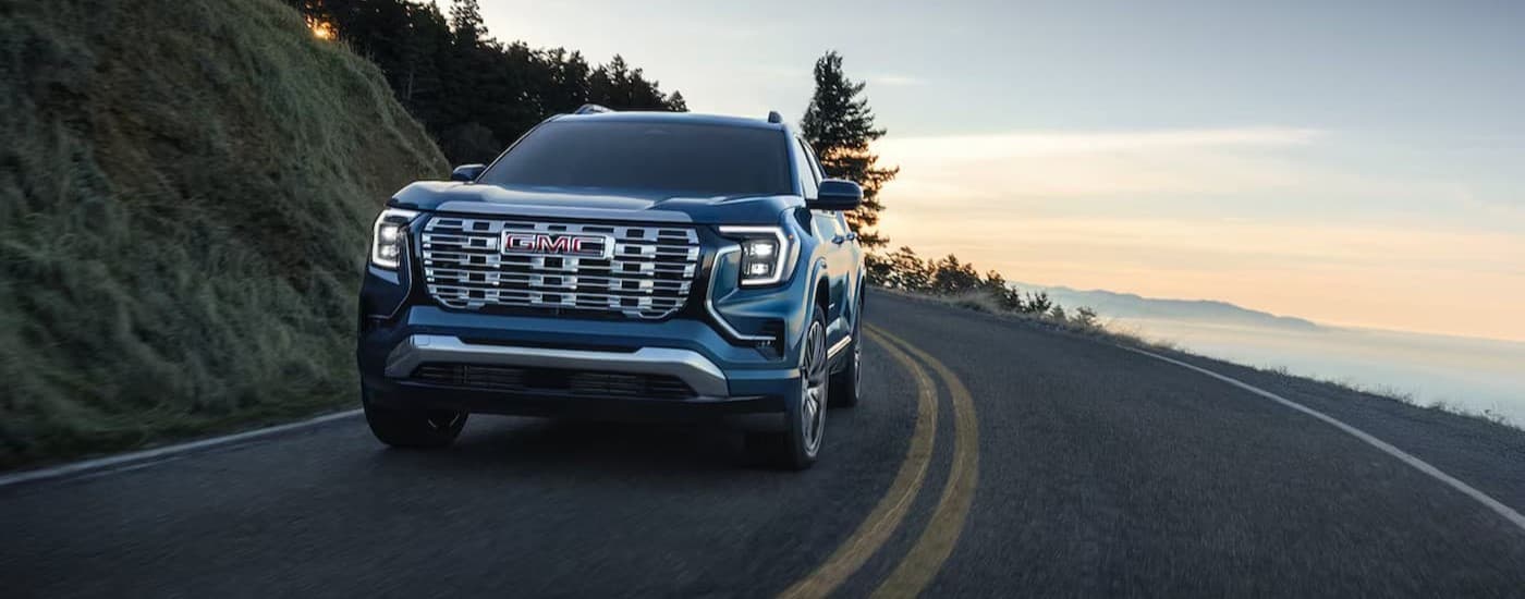 A blue 2026 GMC Terrain driving to vies SUVs for sale.