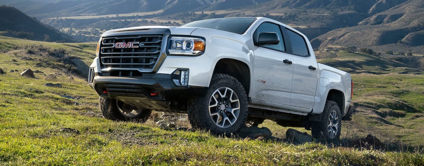 A white 2021 GMC Canyon AT4 off-roading in the mountains.