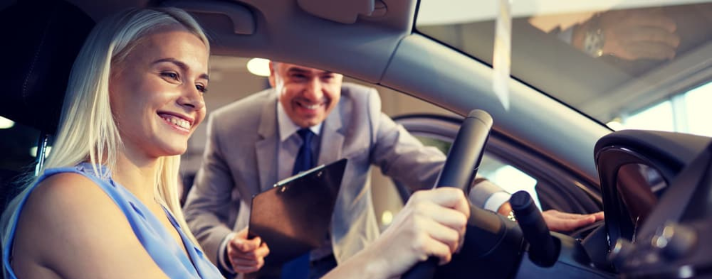 A woman and saleasman at an auto dealership
