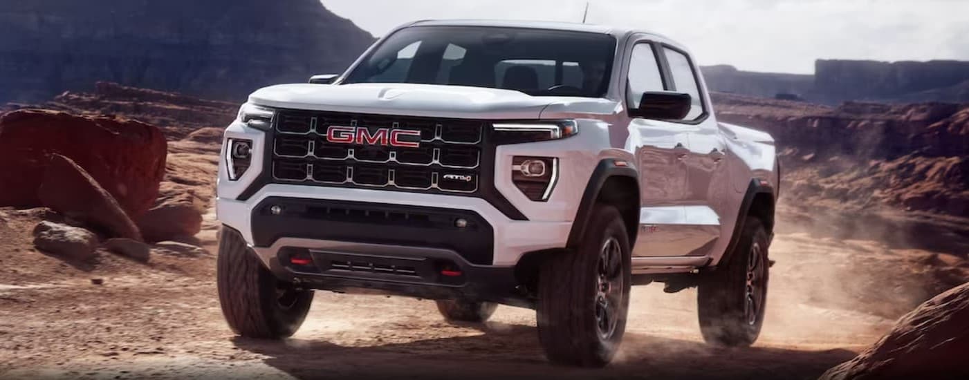 A white 2024 GMC Canyon AT4 parked off-road.